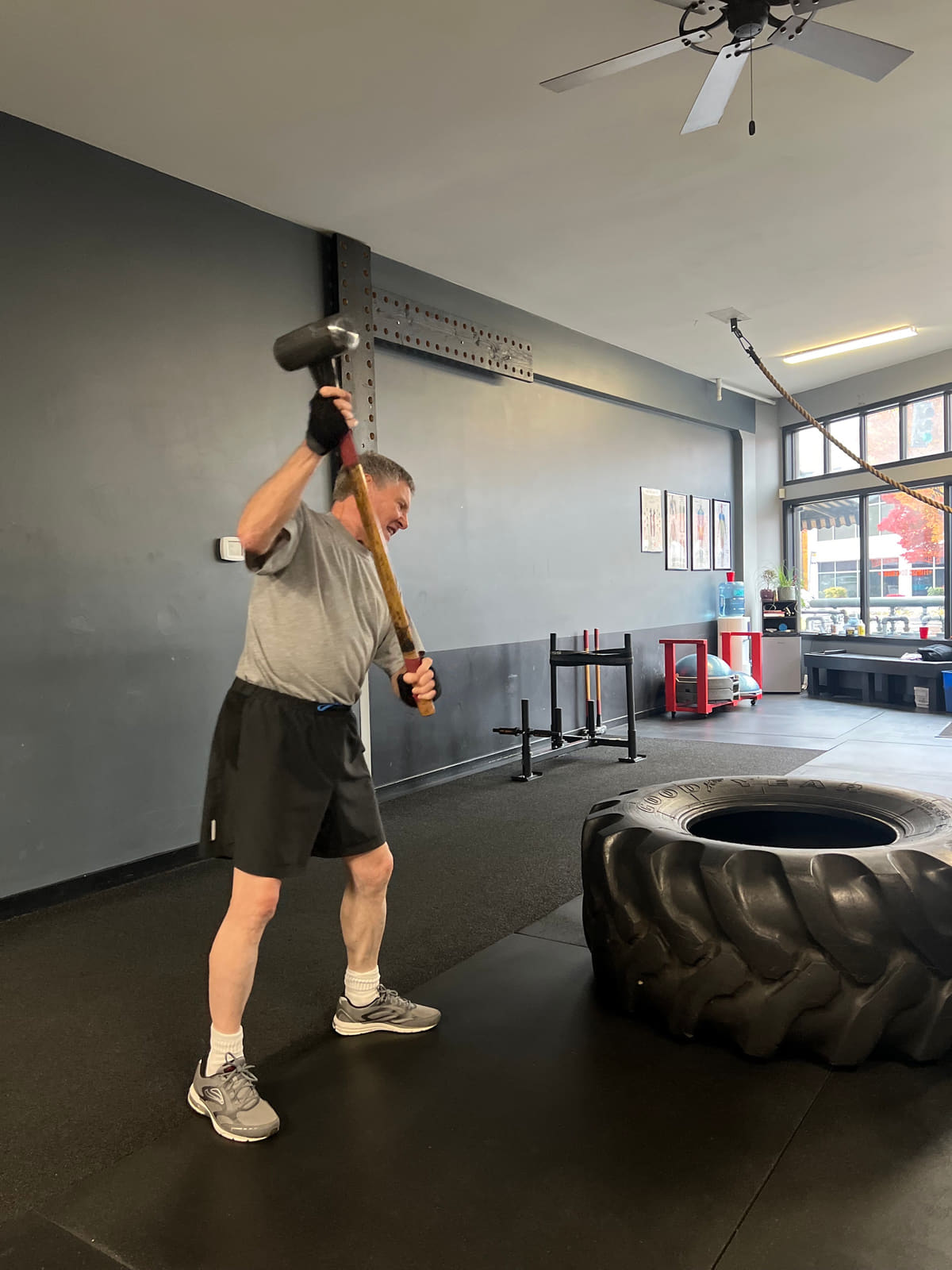 Member swinging a sledgehammer onto a training tire at Seattle Muscle, Seattle